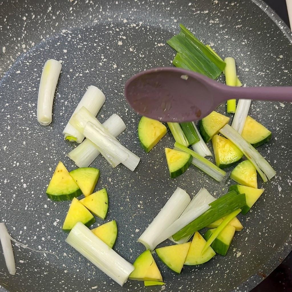 Adding zucchini and scallions to skillet